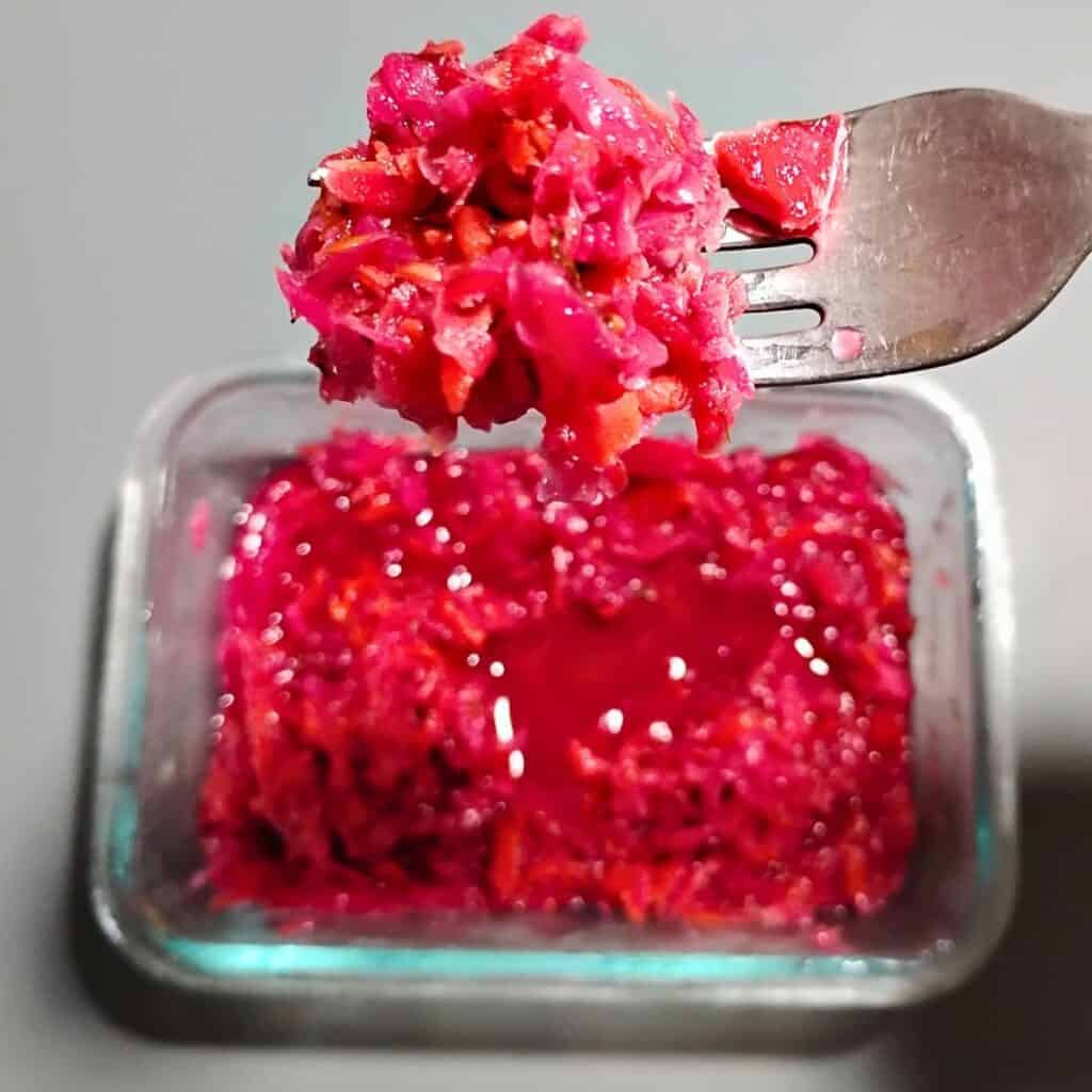 photo shows a dish with some fermented garden slaw and a fork removing some of it.