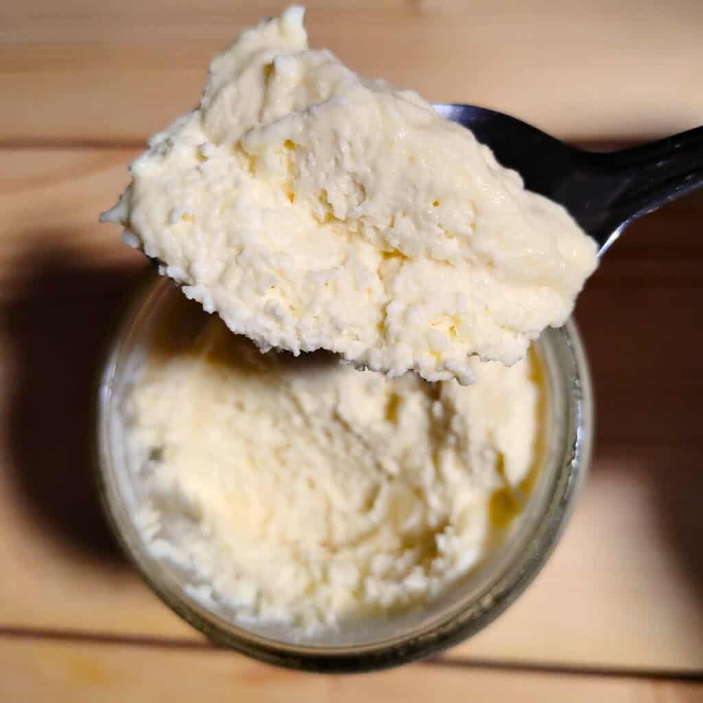photo shows a lemon cheesecake mousse portion on a spoon and a jar filled with it below.