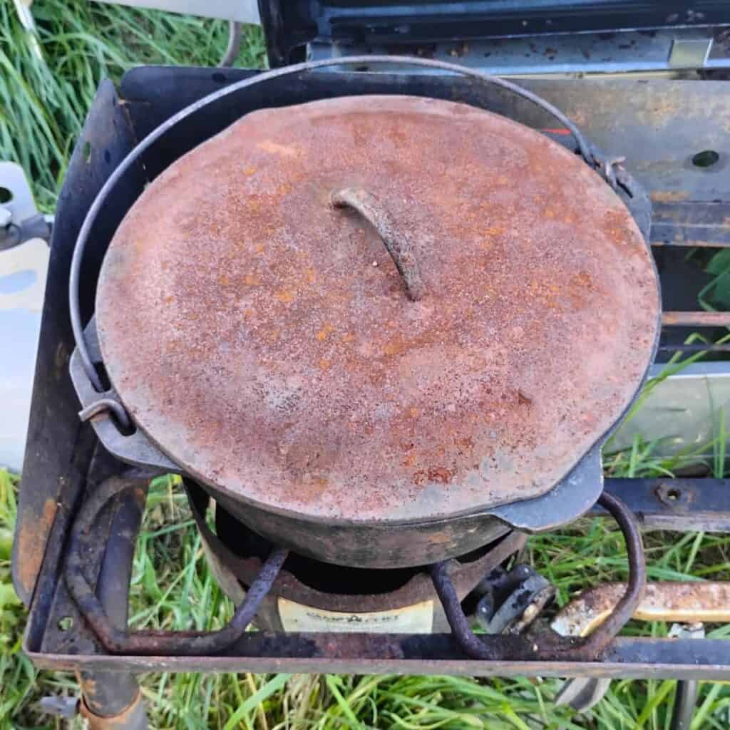 photo shows a dutch oven on a outdoor gas burner with a lid on.