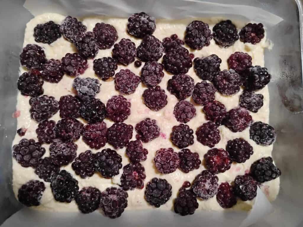 blackberries on top of a creamy cheese filling in a baking dish.