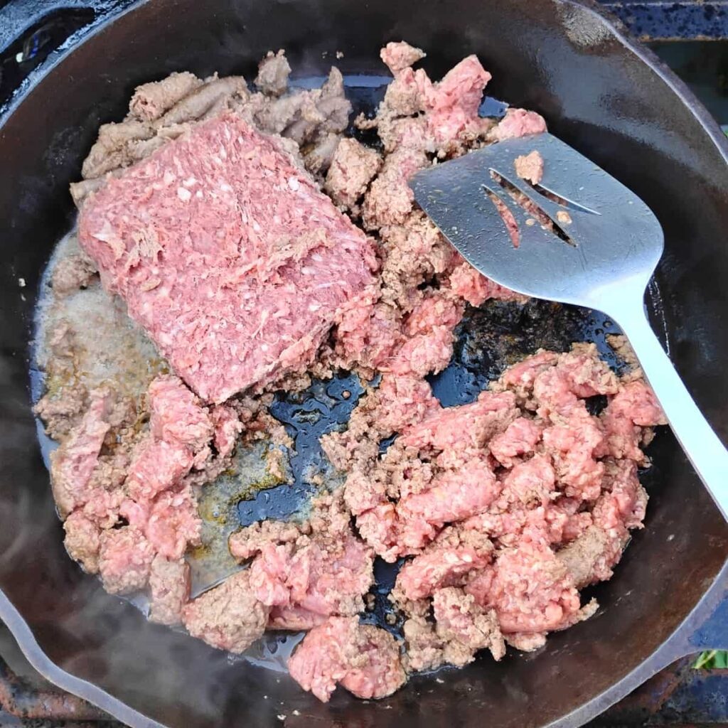 beef is getting fried in a frying pan.