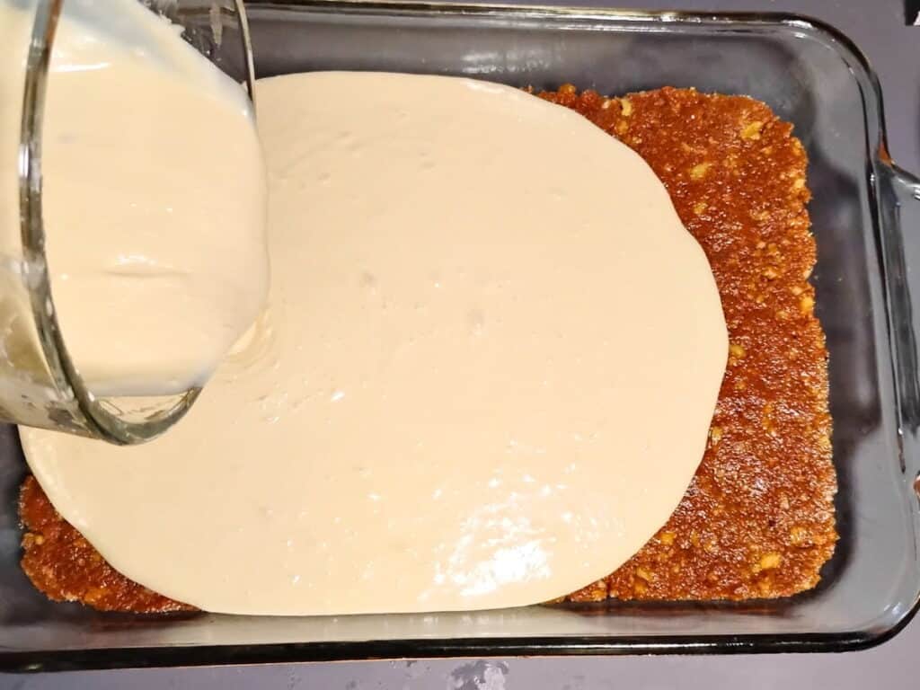 baking dish gets cream cheese filling poured on pie crust.