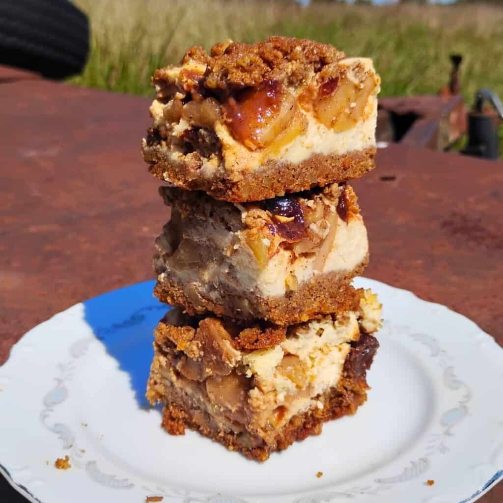 a stack of three apple pie cheesecake bars on a plate.