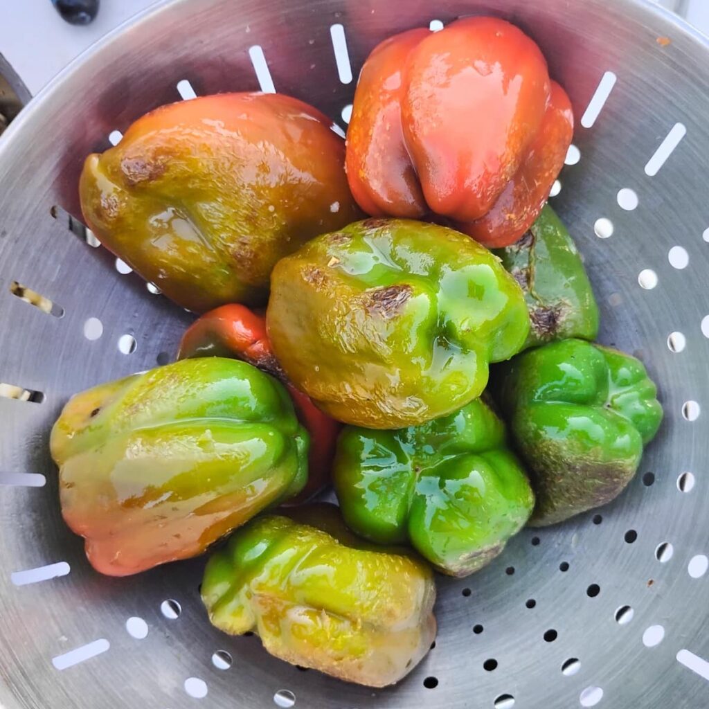 a colander filled with blackened bell peppers ready for stuffing.