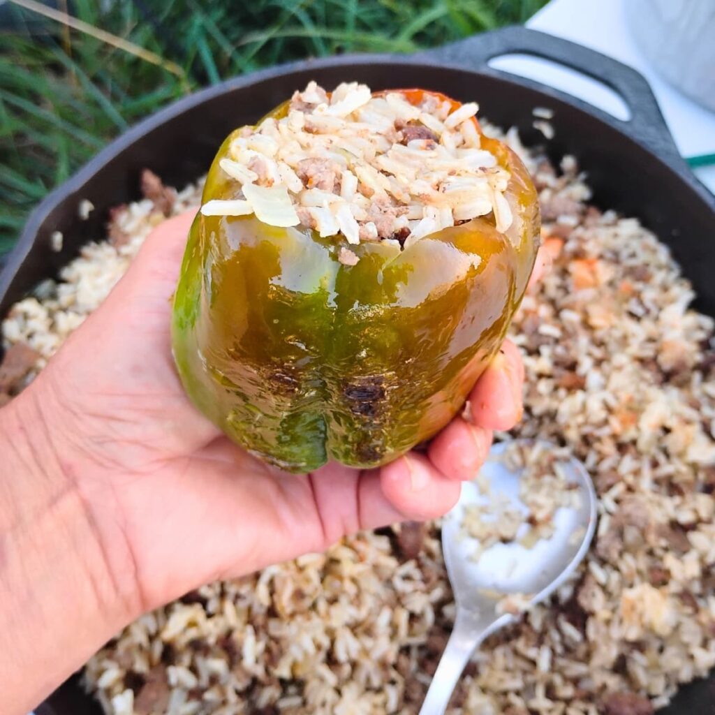 scorched pepper stuffed with rice and beef stuffing in a persons hand, making healthy stuffed peppers.