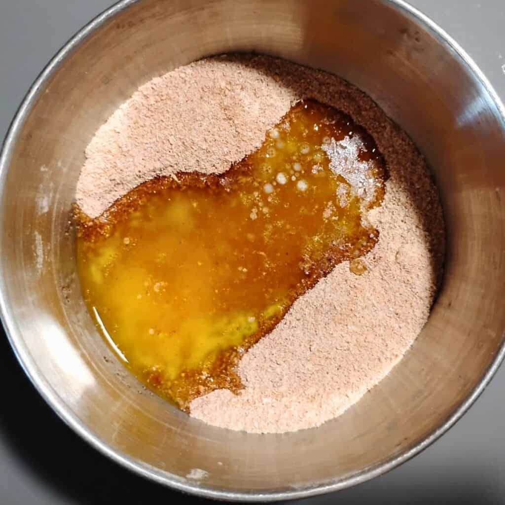 bowl with cake crumble topping ingredients, butter was poured into it.