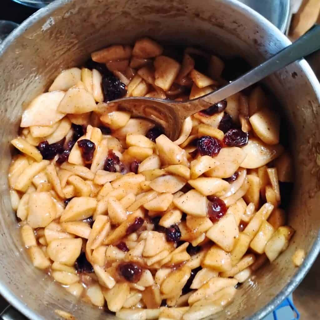a bowl filled with apples, cranberries and spices.