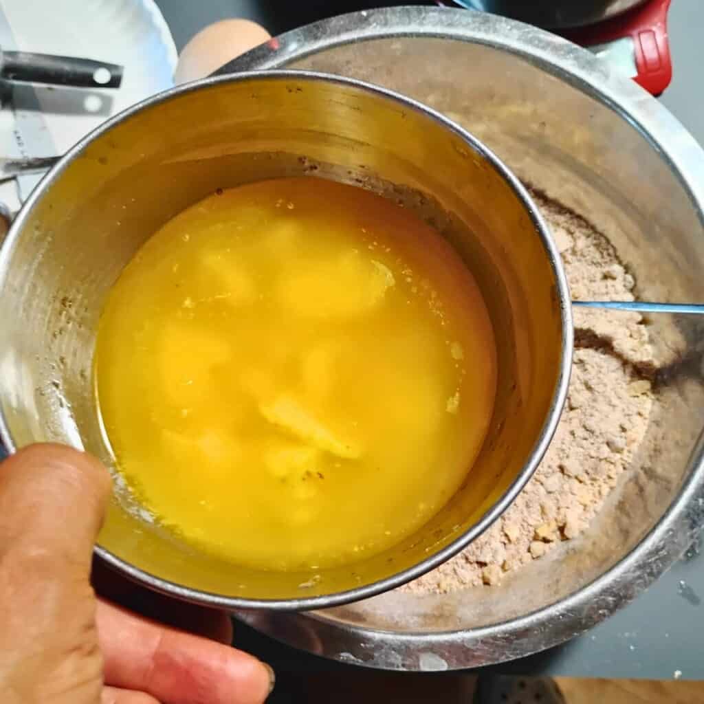 a hand holding a bowl, showing the melted butter.