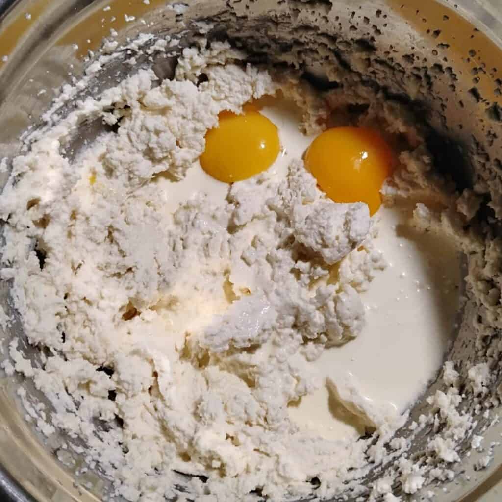 bowl filled with cheesecake ingredients and egg yolks added.