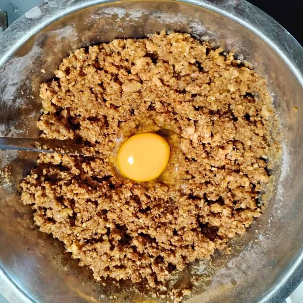 an egg is sitting in a pile of cake crust mixed up in a bowl.
