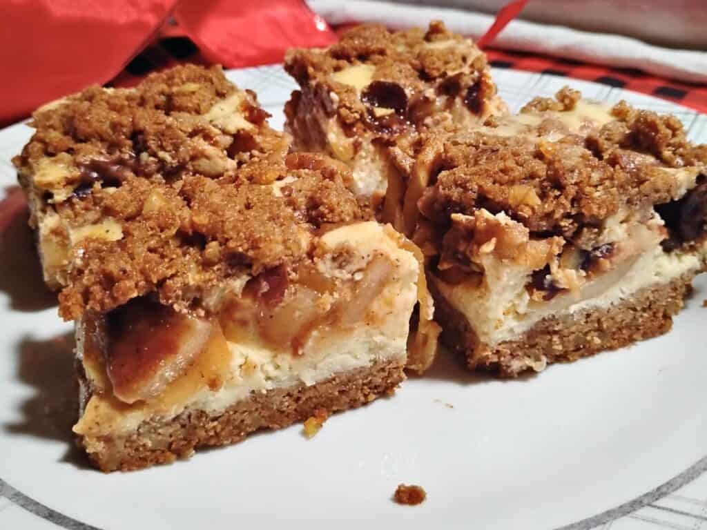 a plate with apple crumble cheesecake bars with a holiday background.