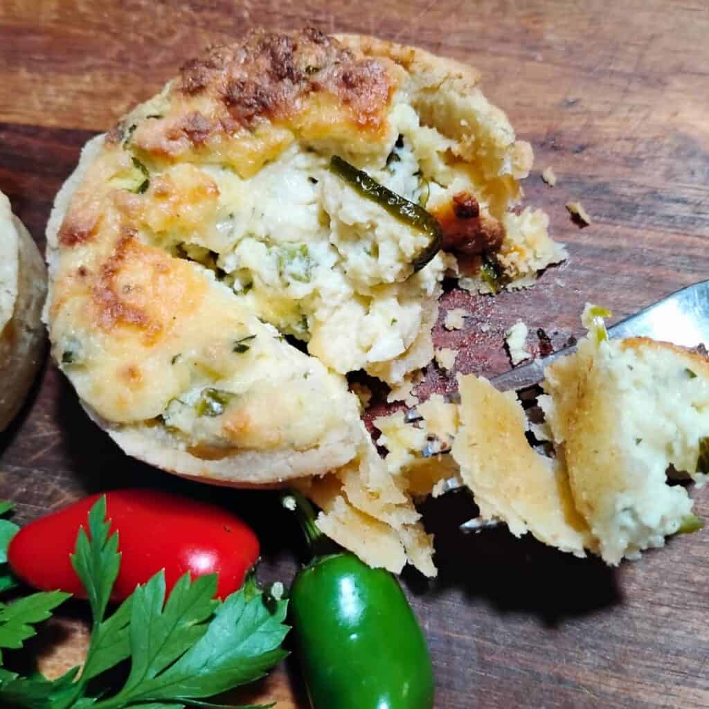 a mini quiche inside a flaky pie crust with a piece removed by a fork. 