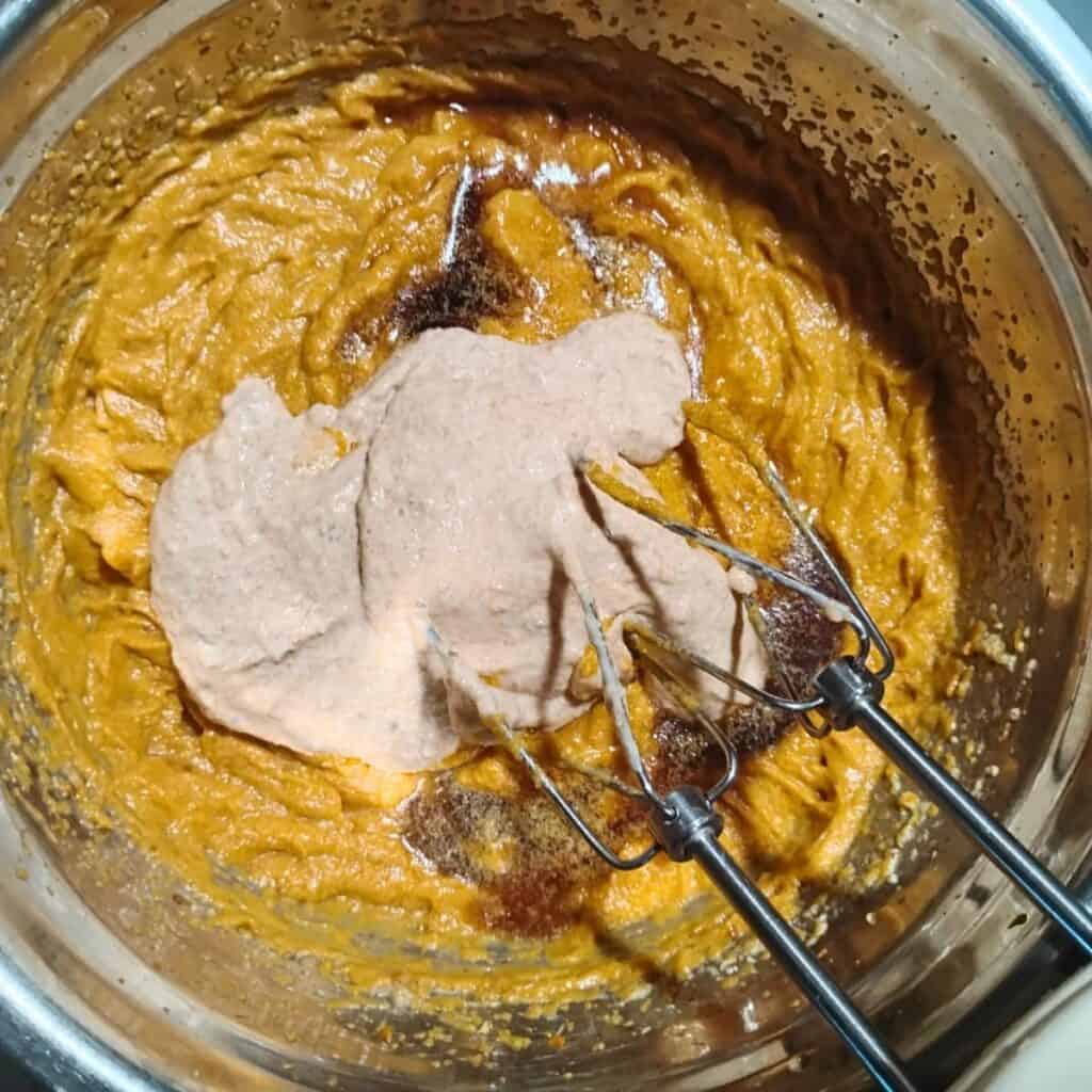 photo shows sourdough and maple syrup getting added to a bowl filled with pumpkin batter. 
