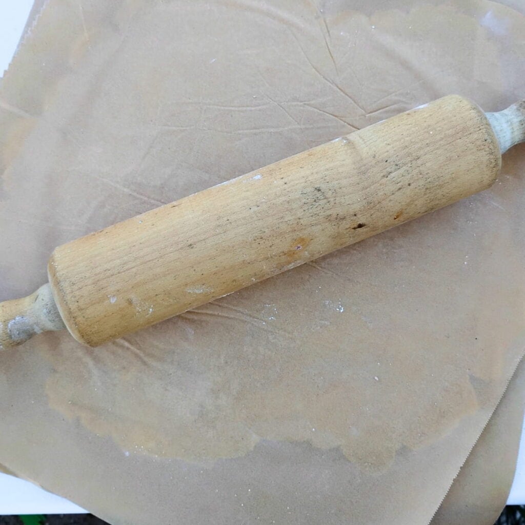 Pie crust is getting rolled out by a rolling pin. 