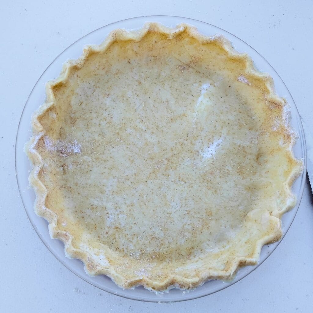 empty. unbaked pie shell in a glass dish with scalloped edges.