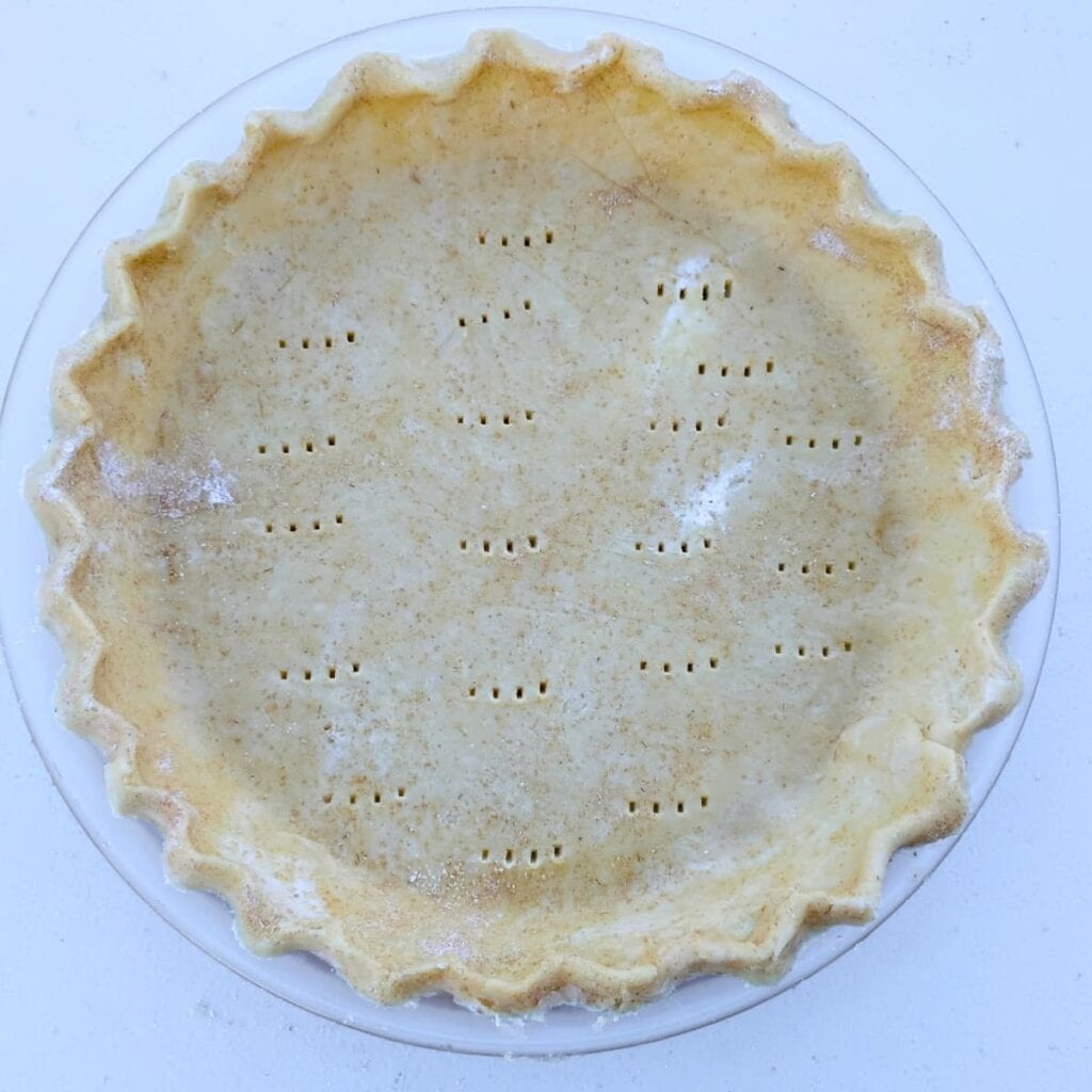 an empty, unbaked pie shell with fork holes poked into the bottom.