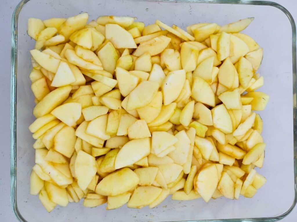 a baking pan half full with sliced apple pieces.