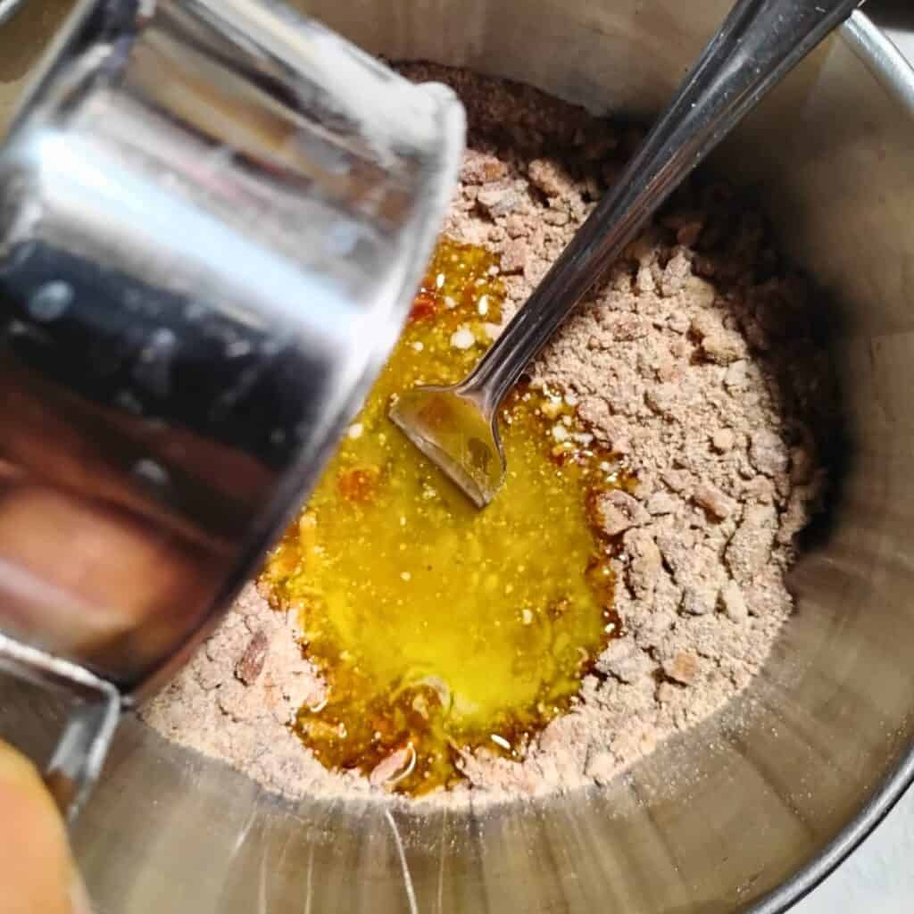 butter gets poured into a bowl with flour, sugar and pecans
