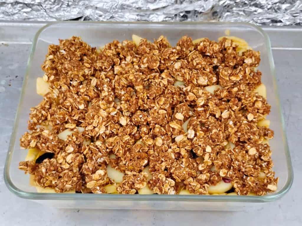 Assembled apple crisp with oatmeal topping, ready for baking in the grill.