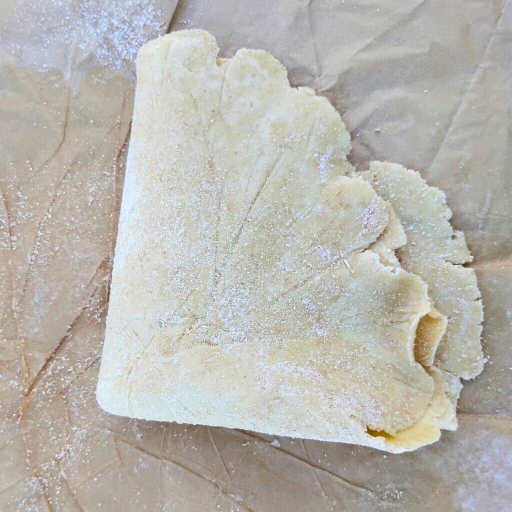 rolled out pie crust folded up to be transferred to the pie dish. 