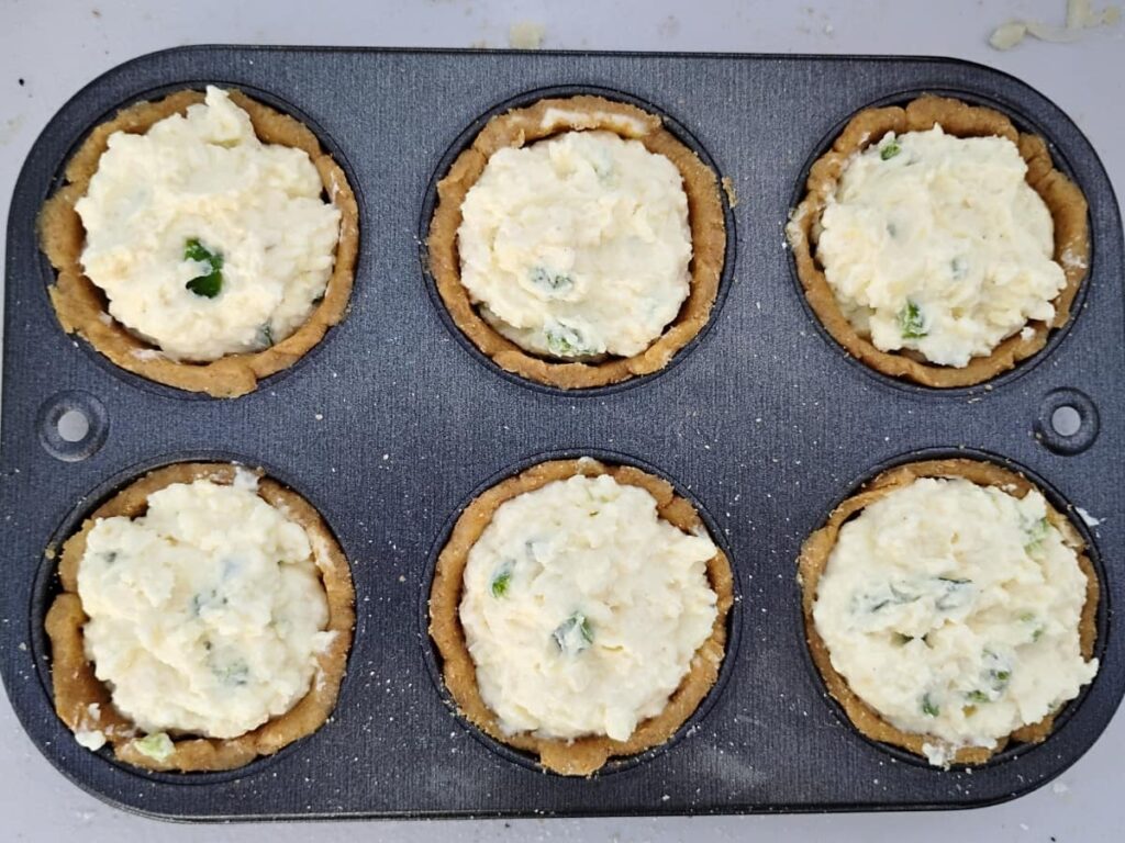 6 muffin cups filled with flaky pie crust and a creamy cheese filling, unbaked and ready for baking. 