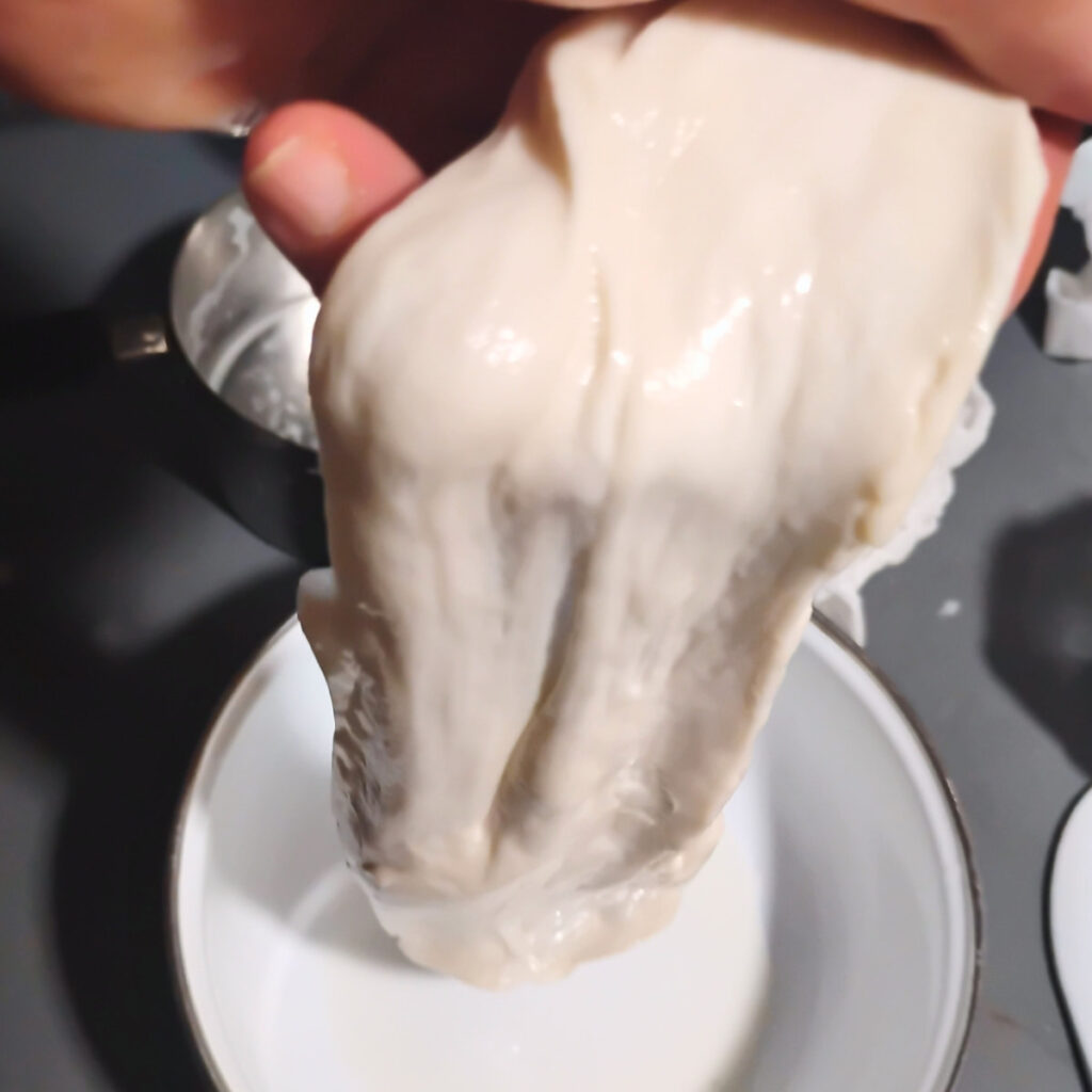 Mozzarella getting stretched in a person's hand