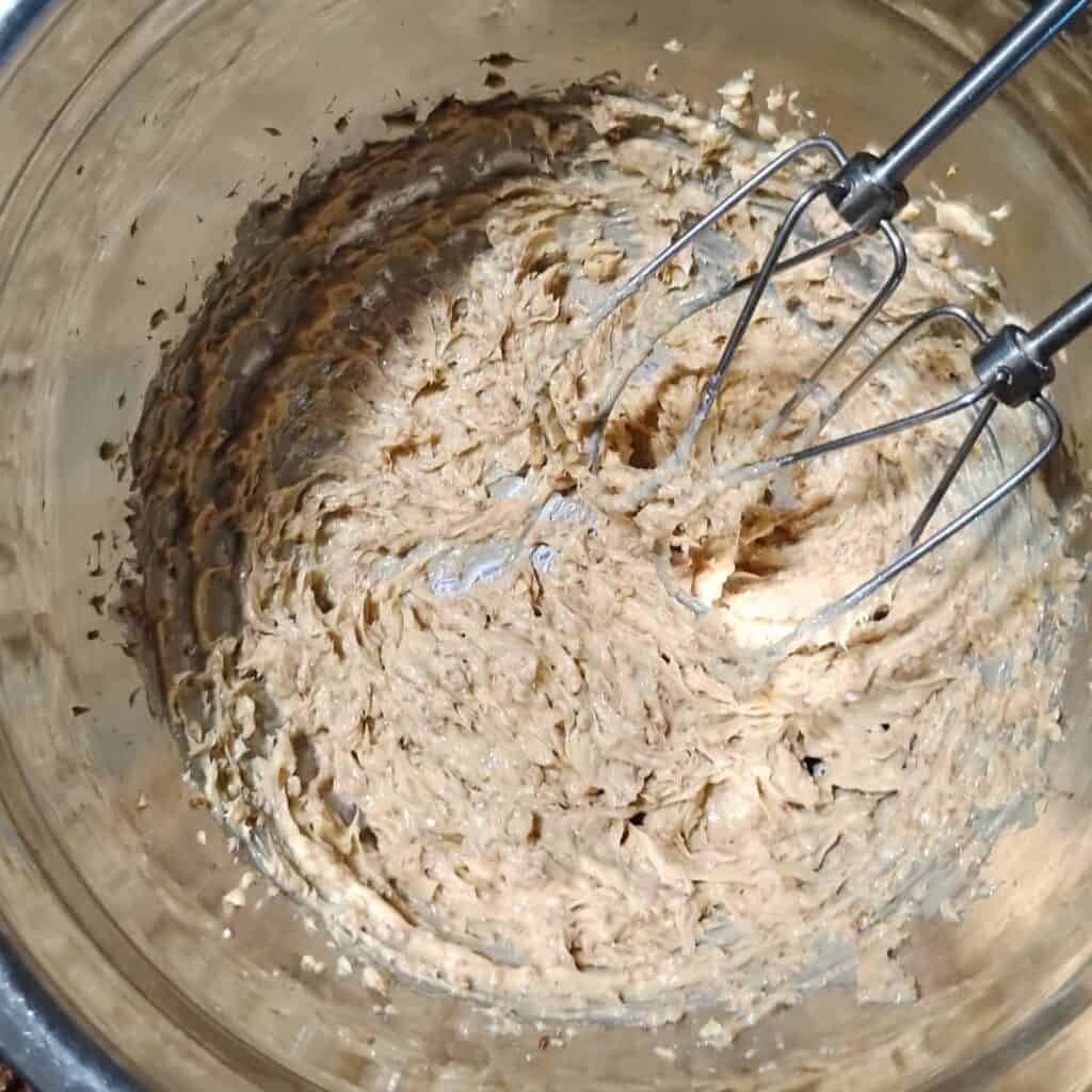 photo of a bowl with butter and panela sugar getting creamed together with beaters of a hand mixer.