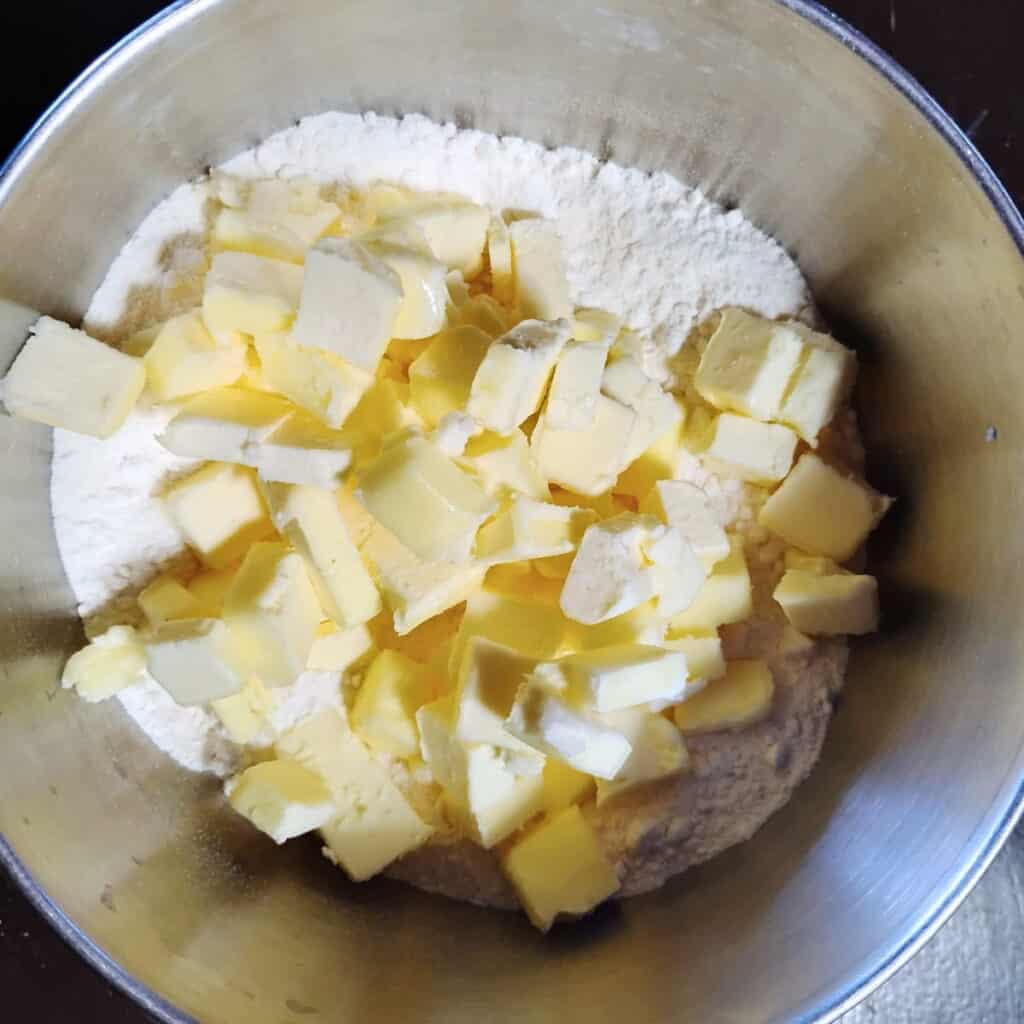 small cubes of butter are added to flour in a bowl.