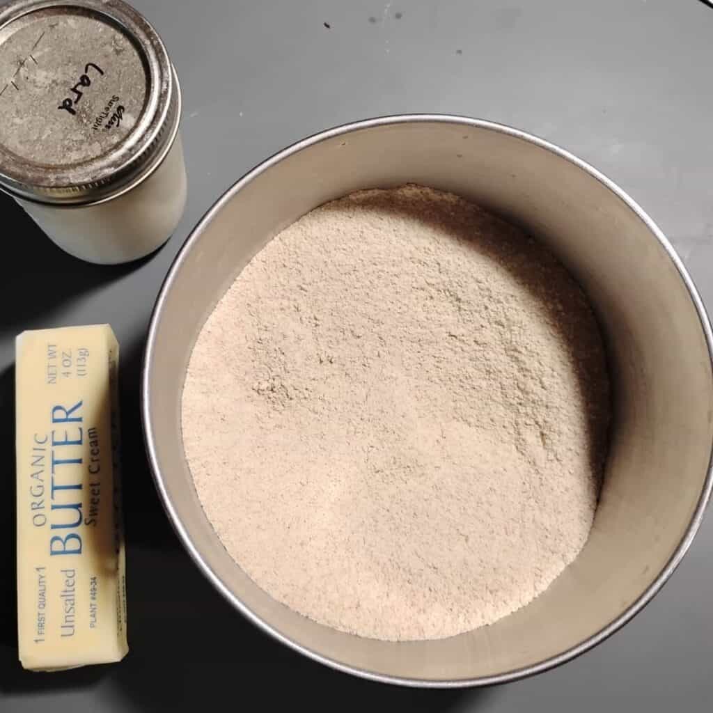 photo of a bowl filled with einkorn flour and with lard and butter next to it. 
