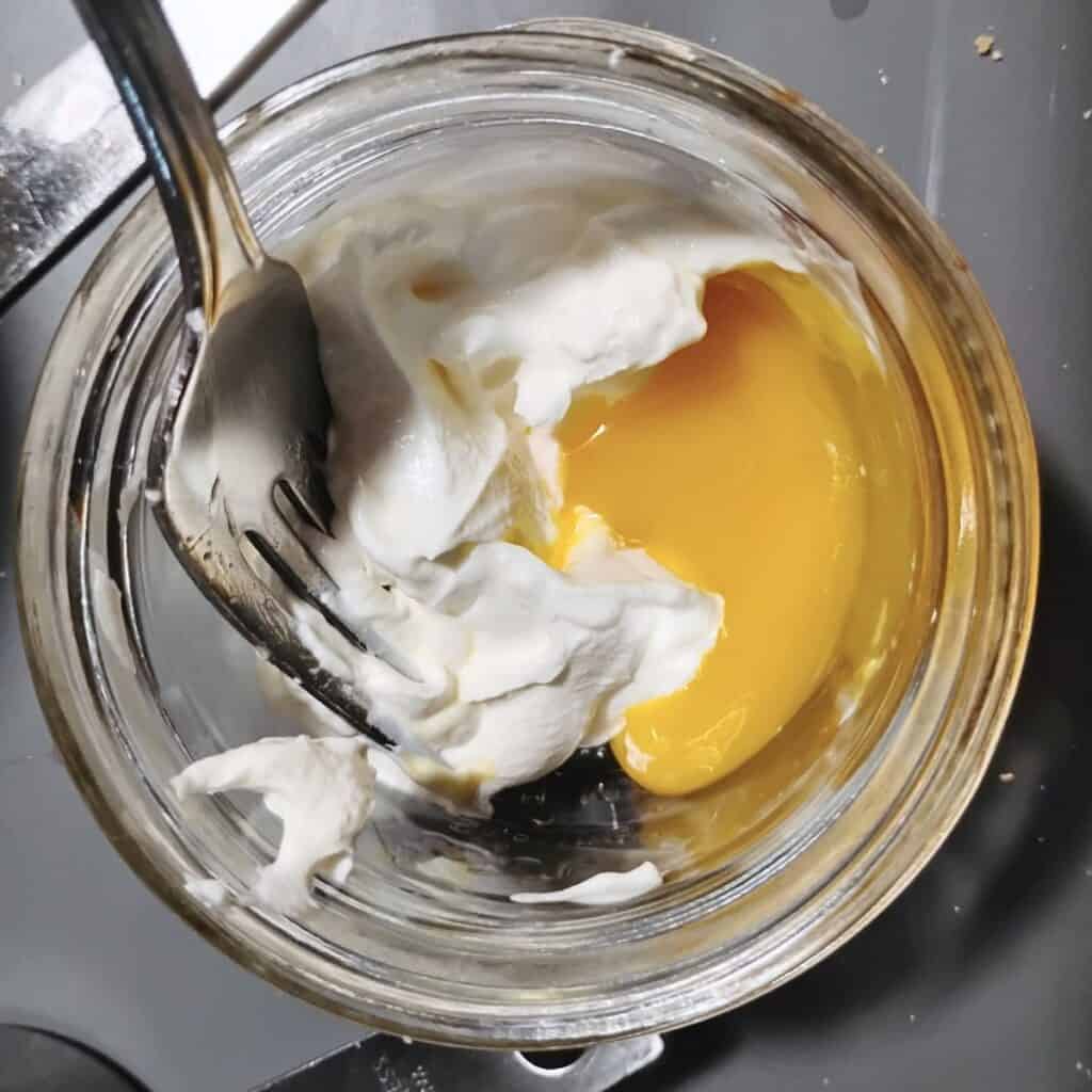 egg and sourcream with some vinegar in a glass dish. getting mixed up with a fork.