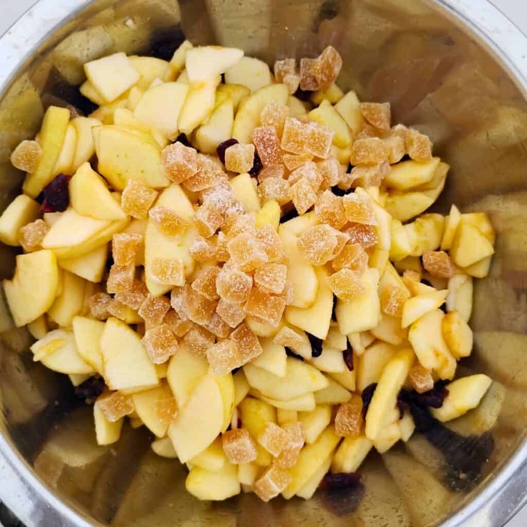 apples, cranberries, and crystallized ginger tossed together in a bowl.