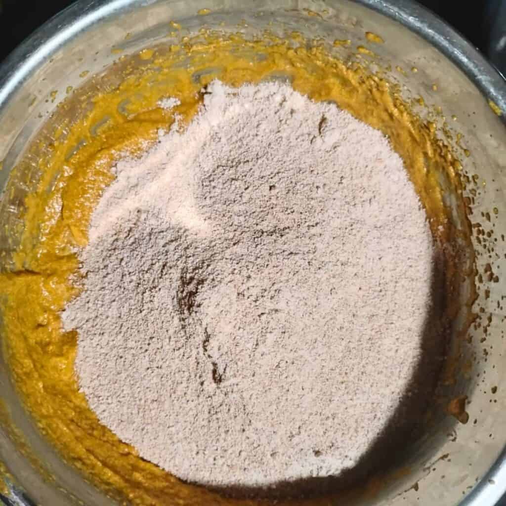 a bowl with pumpkin batter and flour dumped on top. 