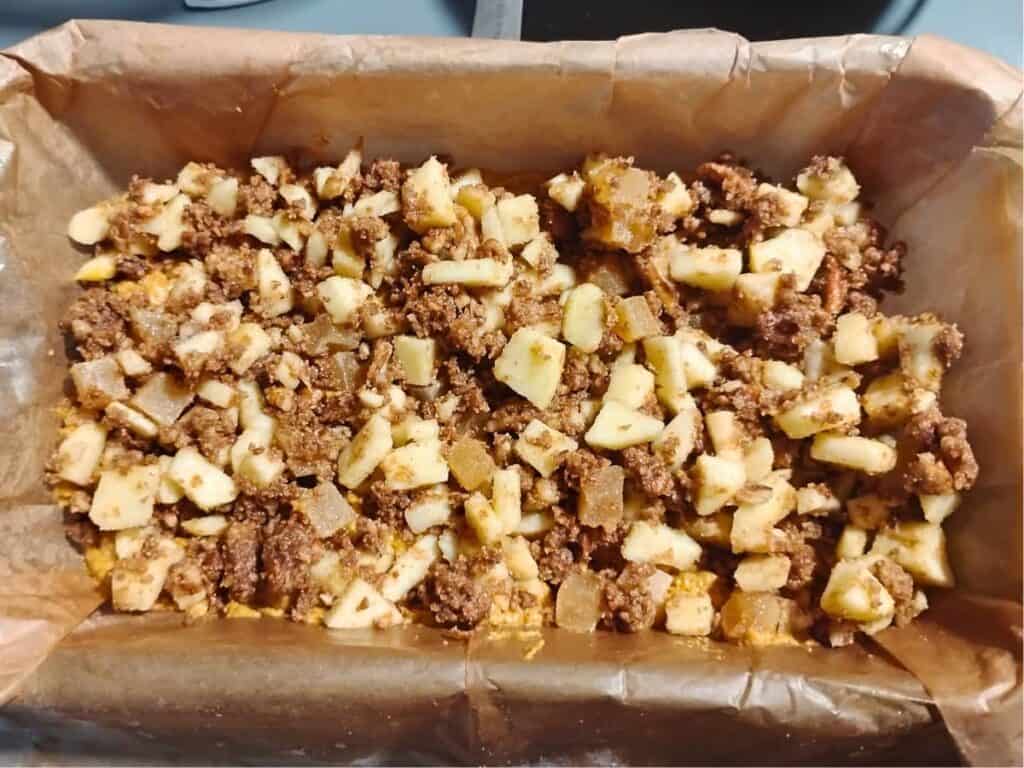 photo shows half of the ingredients layered in a parchment lined loaf pan.