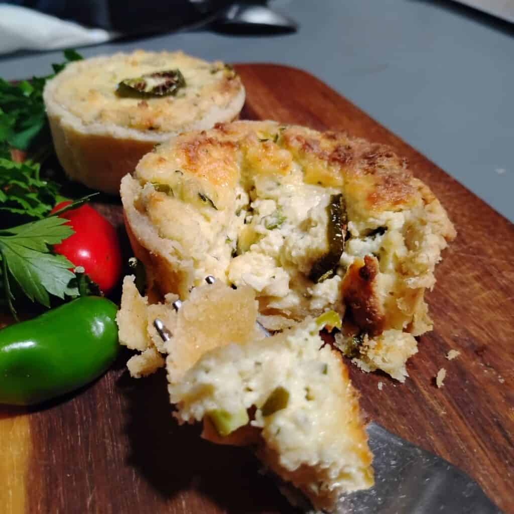 photo shows 2 mini quiches with flaky buttery pie crust and a piece on a fork. With jalapeno and parsley decoration.