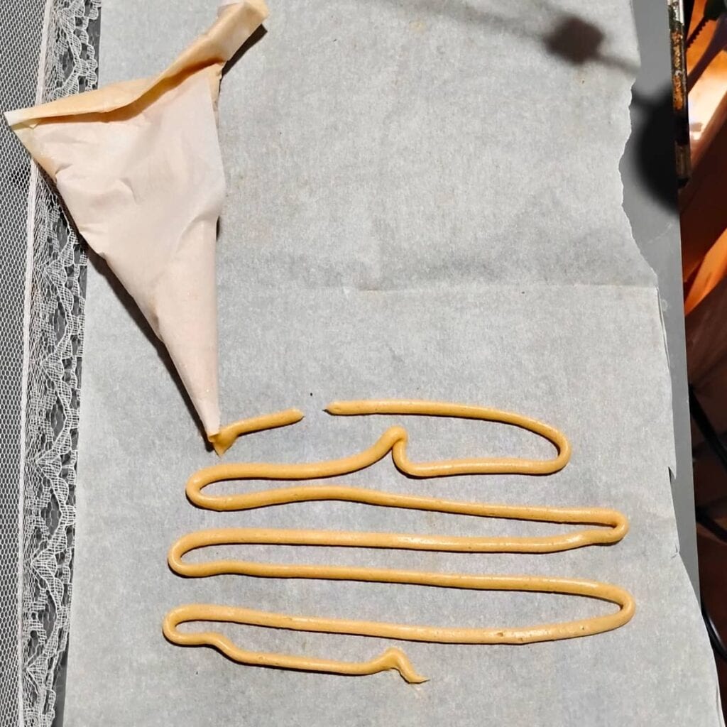 Demonstration of piping a maple glaze on a piece of parchment with a diy parchment piping bag. 