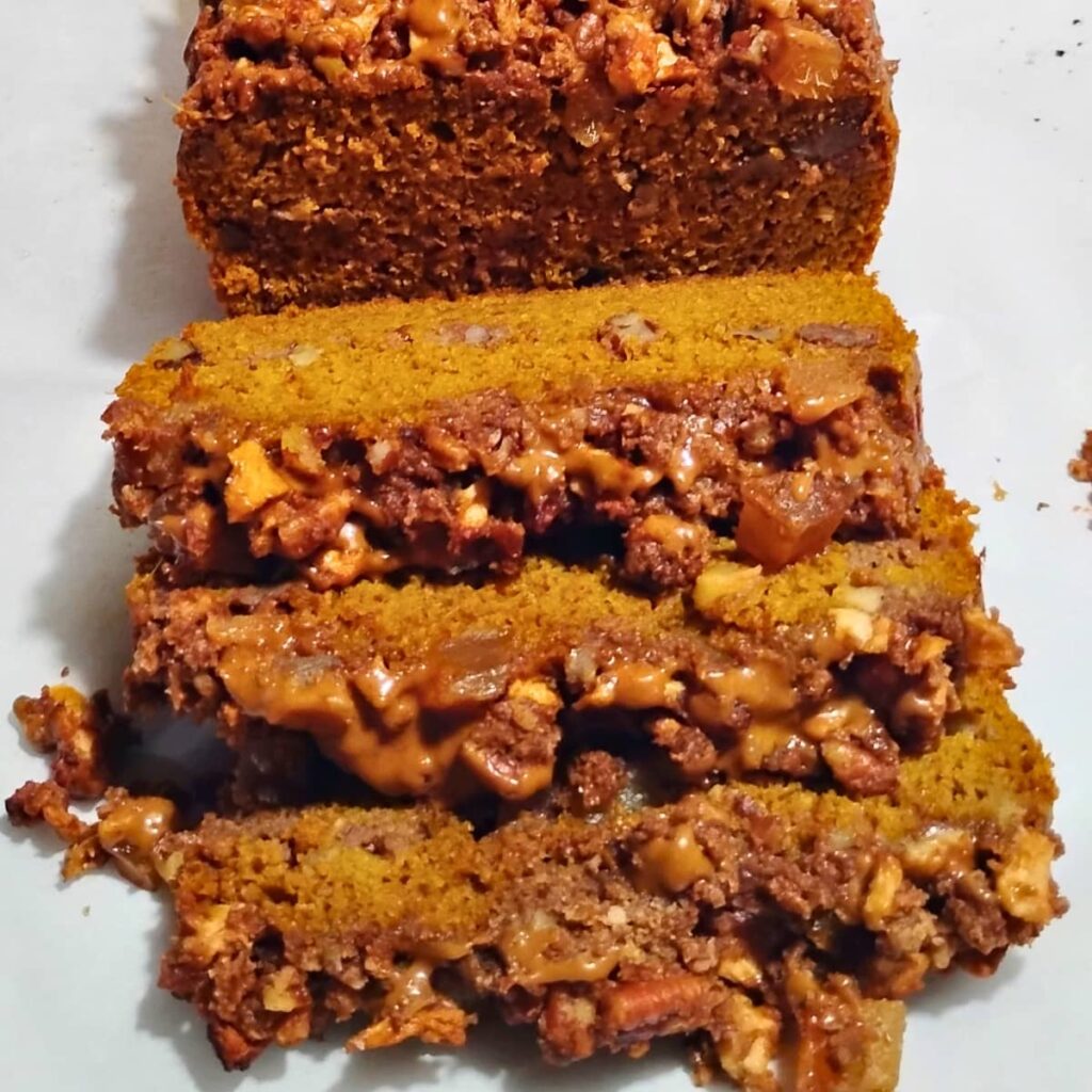 photo of a loaf of sourdough pumpkin coffee cake with some slices showing off the apple pecan and ginger streusel in front.