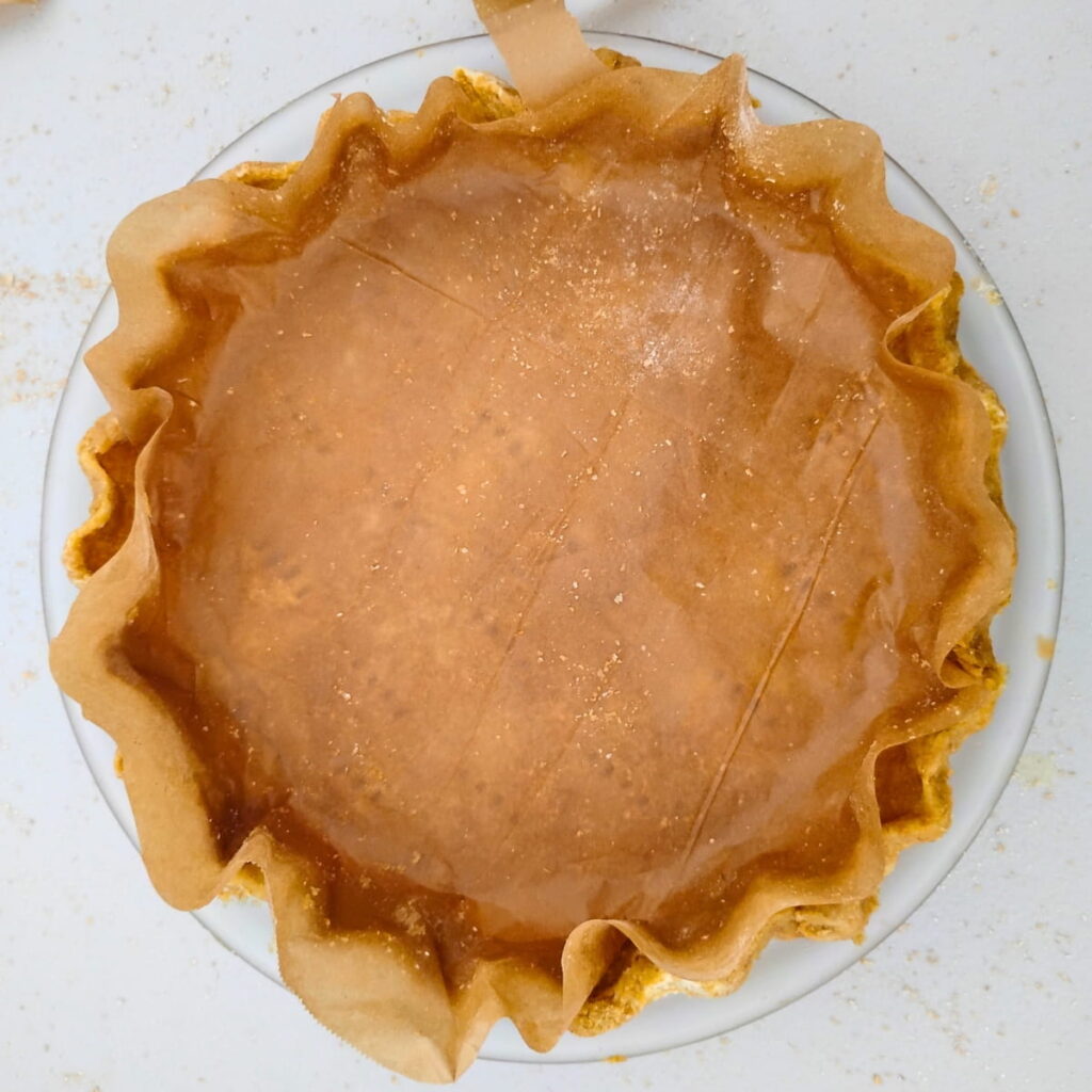 An unbaked pie crust with parchment for blind baking.