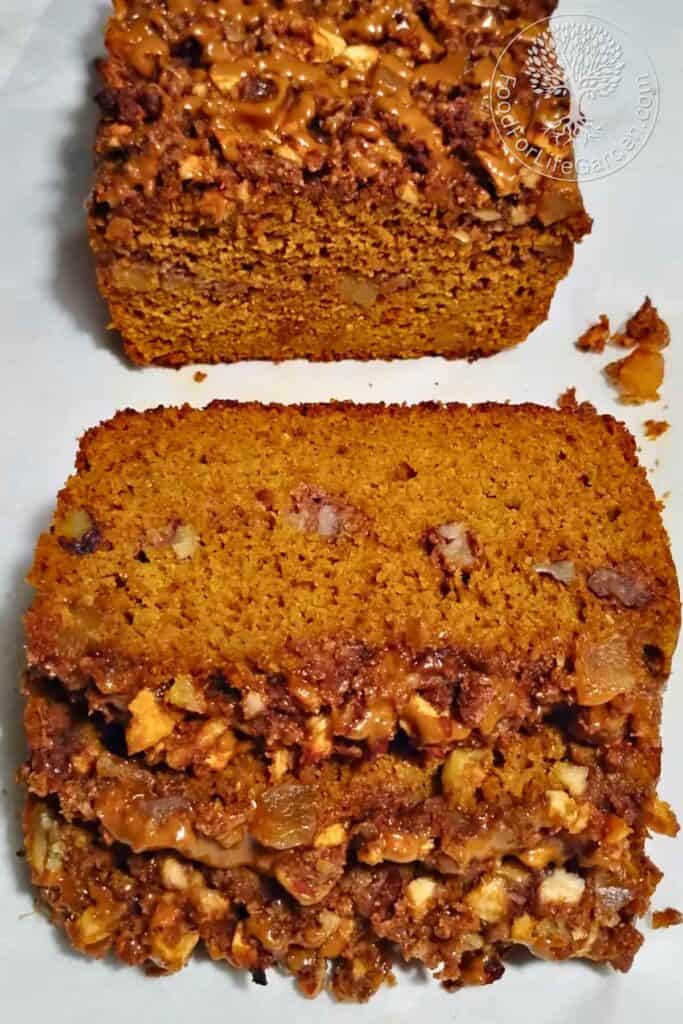 photo of a loaf of sourdough pumpkin cake with ginger, pecan & apple streusel with a few slices cut and laying in front of it. 