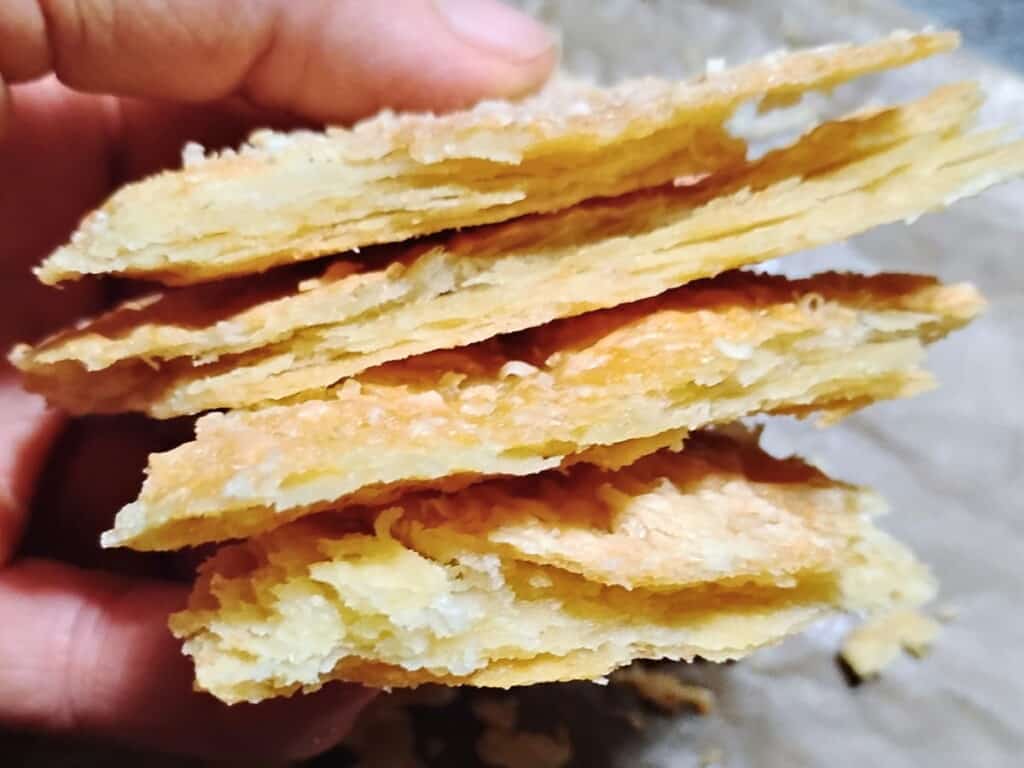 photo of a hand holding several shards of flaky pie crust 