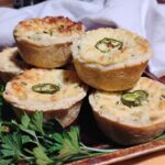 finished jalapeno popper quiche cups stacked on a sheet pan with some parsley in front.