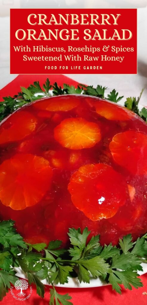 Featured photo shows an un-molded congealed cranberry orange salad on a serving plate surrounded with parsley. text overlay reads cranberry orange salad with hibiscus, rosehips, and spices. sweetened with raw honey. food for life garden.