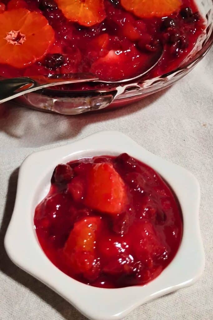 cranberry orange sauce in a pie plate with a spoon. There is a small star-shaped plate in front of it with a portion of the sauce on it.