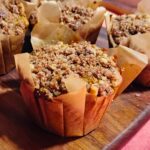 pumpkin apple muffin with ginger, maple syrup, and walnuts on a wooden cutting board.