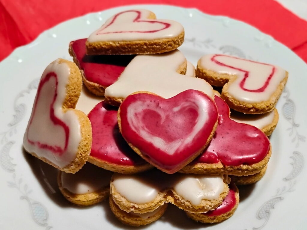 a plate piled high with iced zitronenherzen or lemon heart cookies