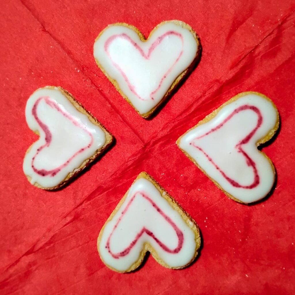 4 heart shaped cookies on a red background.