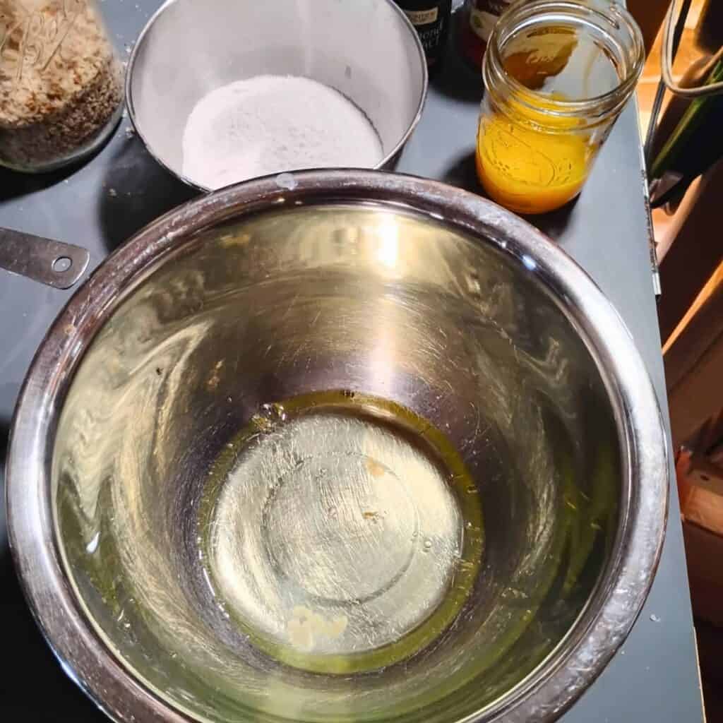 egg whites in a bowl with egg yolks in a glass behind it.