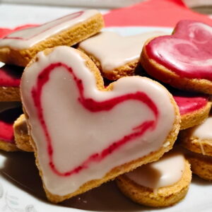 photo of zitronenherzen or lemon heart cookies on a plate frosted with white and red icing.