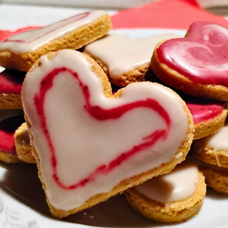 photo of zitronenherzen or lemon heart cookies on a plate frosted with white and red icing.