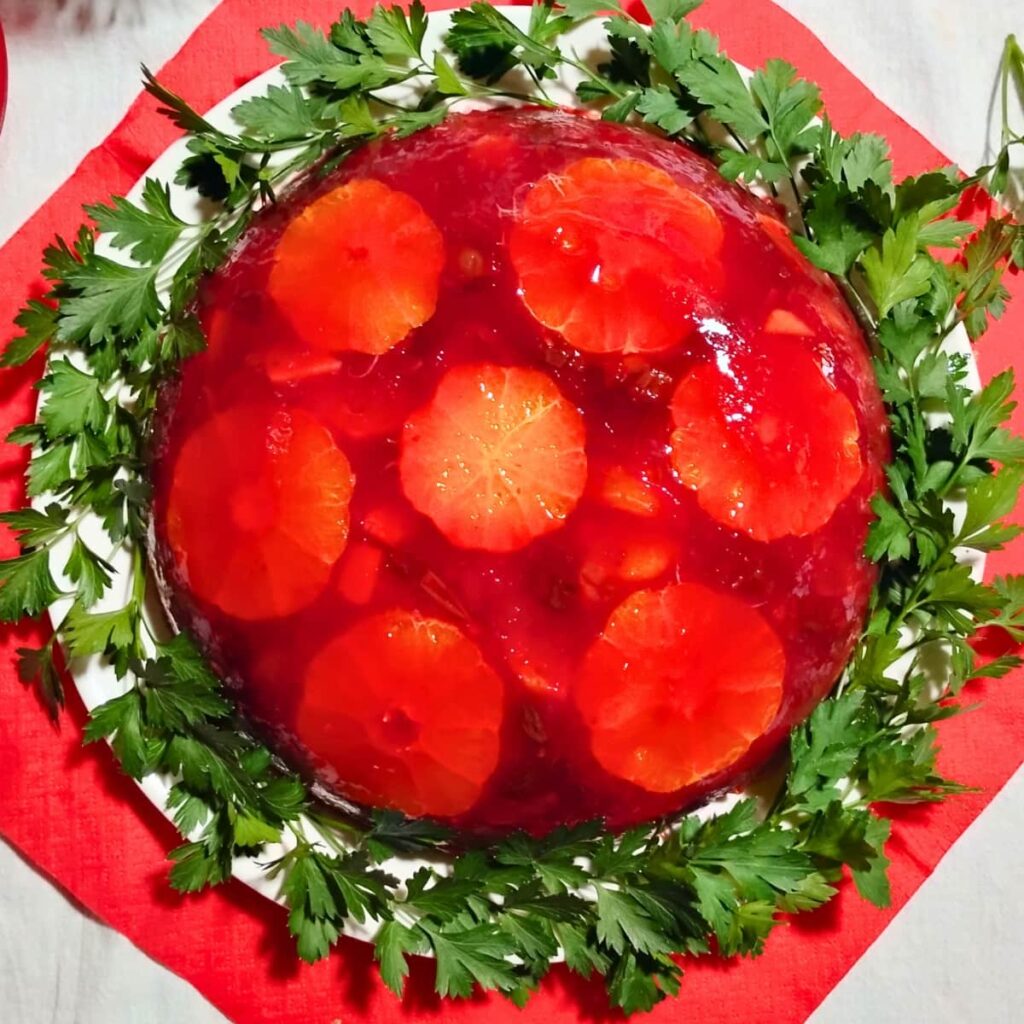 cranberry orange gelatin salad surrounded with parsley on a plate.