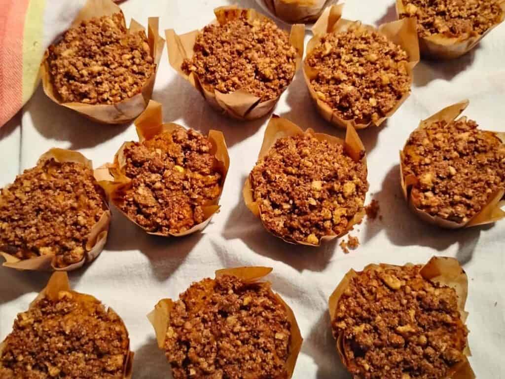 baked muffins in liners sitting on a table cloth.